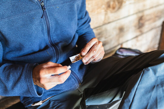 Male Climber preparing cigarette Inside Rustic Hut