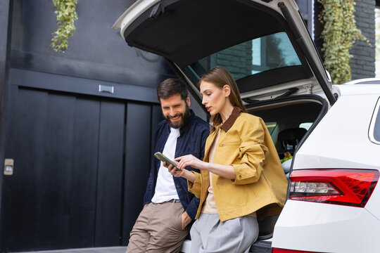 Couple sitting on car trunk