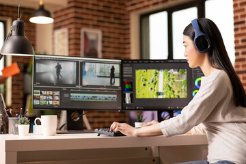 Focused videographer with headphones editing cinematic dance footage at home. Creative editor...