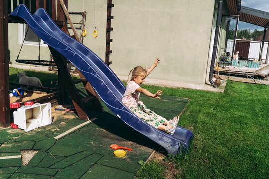 Happy child sliding down a playground slide in backyard