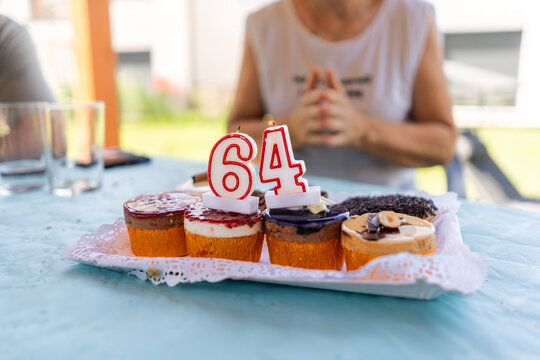 Cupcakes with lit candles celebrating 64th birthday with woman