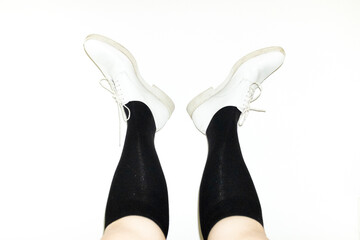 Person wearing white lace up shoes with knee socks with flashlight