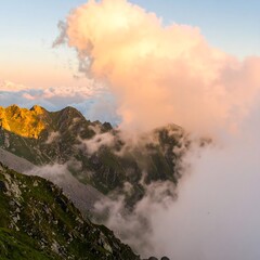 Mountain peaks shrouded in colorful clouds at sunset