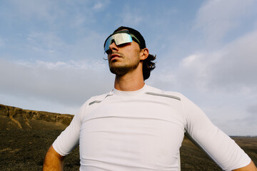 Fit man wearing a cap and sports sunglasses gazing at the horizon