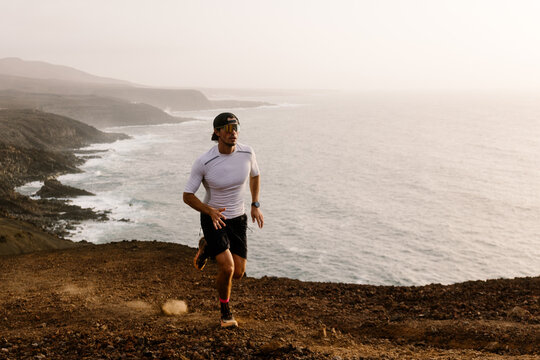 Wide view capturing a runner moving uphill near the coast