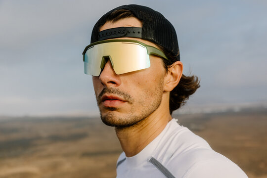 Close-up portrait of an athletic man wearing sports sunglasses and cap