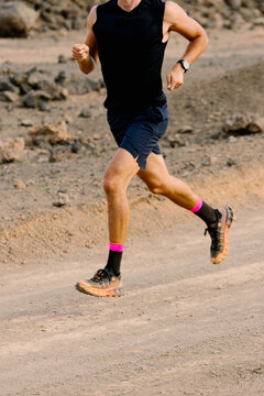 A fit unknown man running on a dirt path while training trail running