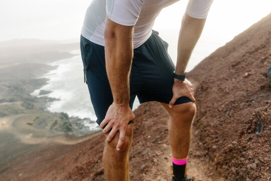 Anonymous trail runner resting leaning on his knees