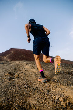 Low-angle shot of a trail running runner climbing a rocky trail