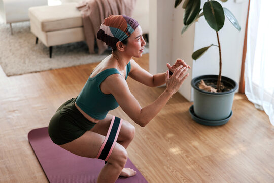 Woman doing squats with resistance band at home.