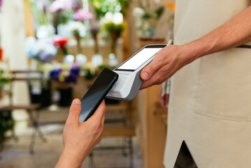 Anonymous hand using smartphone to pay in a cute restaurant 

