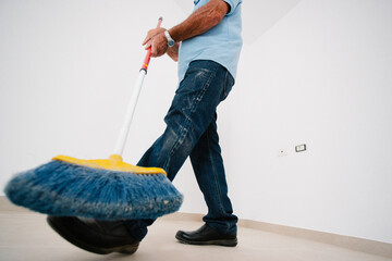 Wide upside-down shot of an elderly man sweeping dust
