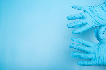 Fototapeta premium Hands in blue gloves on a blue background, space for text, a place for a picture