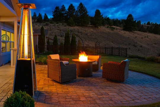 Pyramid patio heater and flaming fire pit warming a residential outdoor deck with seating on a cold evening.