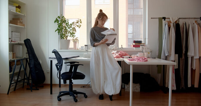 Fashion designer reviewing sketches in bright studio