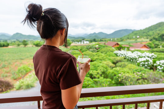 Asian woman drinks iced green tea at scenic roadside cafe
