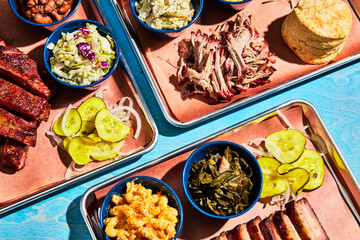 Southern BBQ Feast with Sides on Metal Trays on a Blue Table