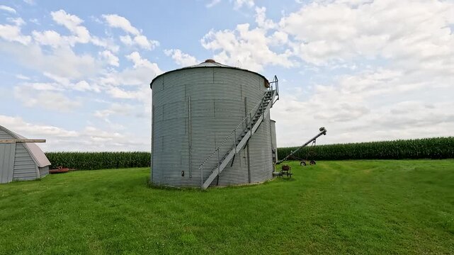 Corrugated Steel Grain Bin with Stairs, Handheld Walk Toward, Turning Camera Up Stairs, Cornfield and Auger in Background