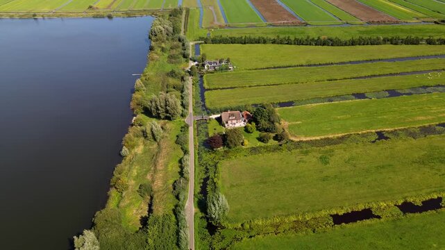 Aerial view of a rural landscape with a central road, water body, irrigated fields, and scattered houses. The scene highlights agricultural planning and natural integration.
