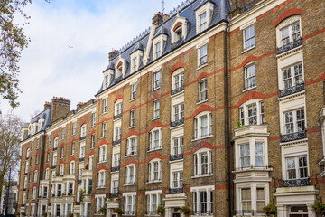 Old towering brick apartment block in central London on a partly cloudy winter day
