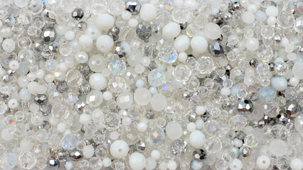 Close up of white, silver, transparent and matte crystal beads flat lay background