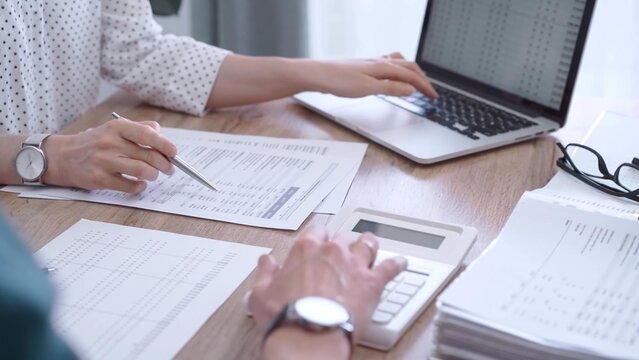 Professional female bookkeeper or auditor are working on business finances with a colleague, using calculator and laptop. Finance audit and taxes