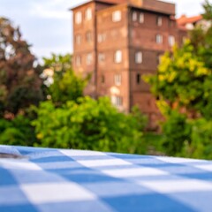 Outdoor patio table with checkered tablecloth, out-of-focus building in the background