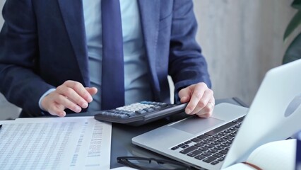 Fototapeta premium Businessman analyzing financial data on laptop and calculator. Close-up of a professional auditor working on financial reports. Business concept