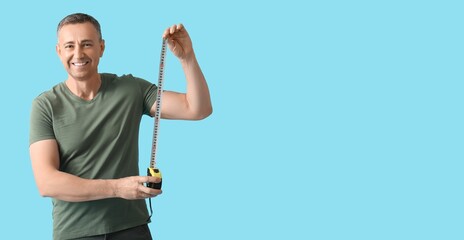 Middle-aged man with tape measure on blue background with space for text