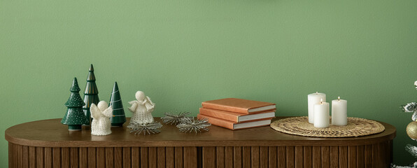 Christmas decor and burning candles on chest of drawers in room. Closeup