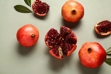 Fresh pomegranates and leaves on green background
