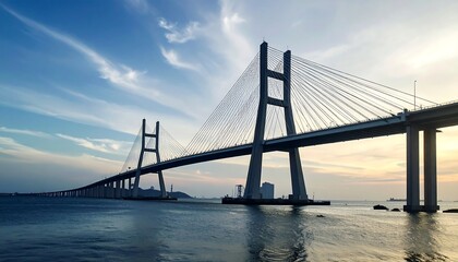 Obraz premium Silhouette of a modern cable-stayed bridge at sunset over water