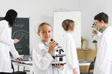 Teenage girl with microscope in Biology class at school