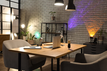 Interior of dark studio with podcaster's workplace, shelf unit and glowing lamps