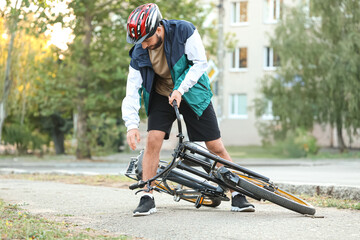 Young man getting up after falling off his bike outdoors