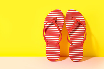 Pair of stylish flip-flops on yellow background, closeup