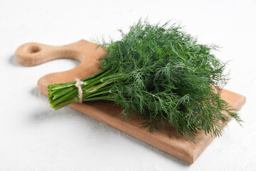 Wooden board with bunch of fresh green dill on white background, closeup