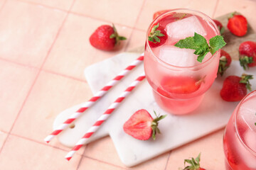 Glass of tasty cold cocktail with strawberry on pink tile background, closeup
