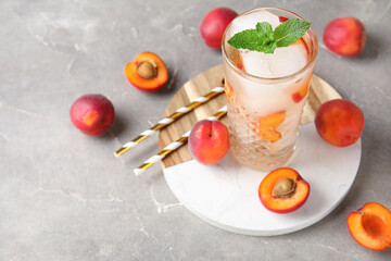 Glass of tasty cold cocktail and apricots on grey grunge background, closeup