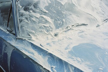 Analog close-up of a royal blue car being washed, the surface completely covered in soap scum. The foam is thick and uneven, streaking the windows and metal body in expressive gestures