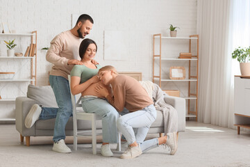 Young happy pregnant woman sitting on chair with her husband and doula at home