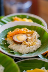 Authentic Indonesian food, Nasi Liwet or Nasi Ayam, white rice served with shredded chicken, marinated egg, and vegetables on banana leaf. Perfect for culinary, cultural, and travel concepts.
