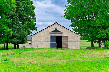 Obraz premium Brick farm building with wide gates standing in an open field