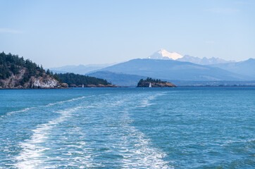 Telephoto view of Mt Baker in hazy distance over Samish Island near Anacortes in Washington State with ships wake leading line