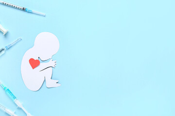 Paper baby figure with heart and syringes on blue background. IVF concept