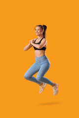 Young happy sporty woman jumping on yellow background