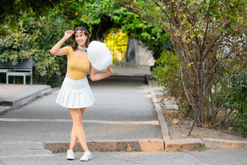 Beautiful young happy woman with cotton candy in park, outdoors