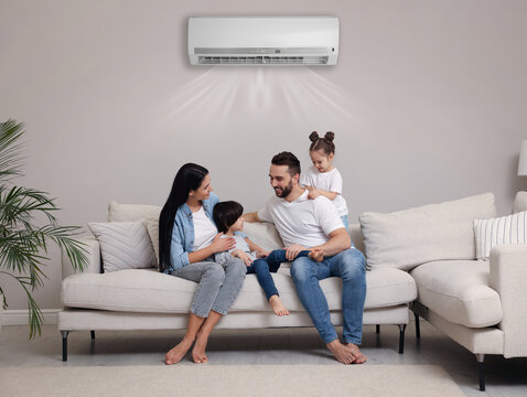 Happy family on sofa in living room. Air conditioner keeping comfortable temperature in room - Powered by Adobe