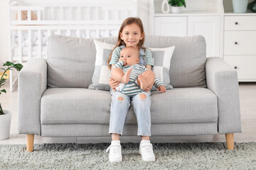 Obraz premium Little girl with her baby brother sitting on sofa at home