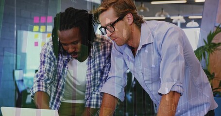Leaning over laptop, two colleagues scanning data charts in office, with sticky notes
